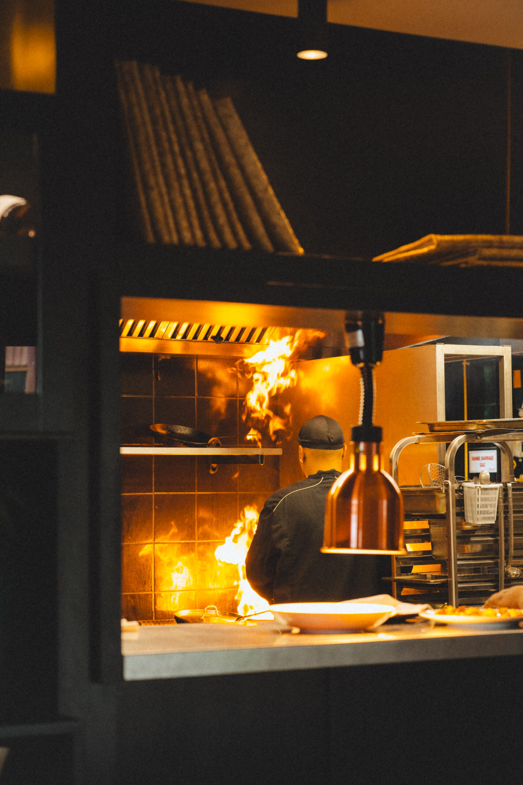 Chef du Tuit-Tuit en cuisine, derrière le passe, dans une ambiance chaleureuse et intimiste.